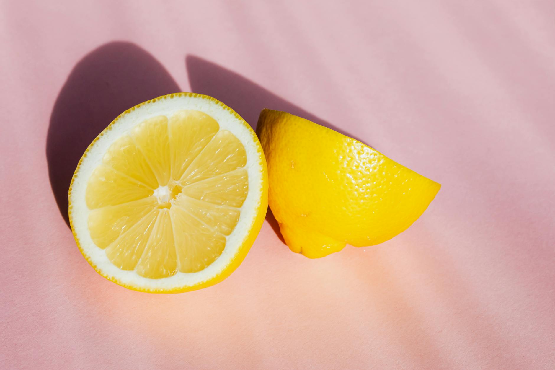 Fresh lemon halves on a pink background, symbolizing freshness and recovery