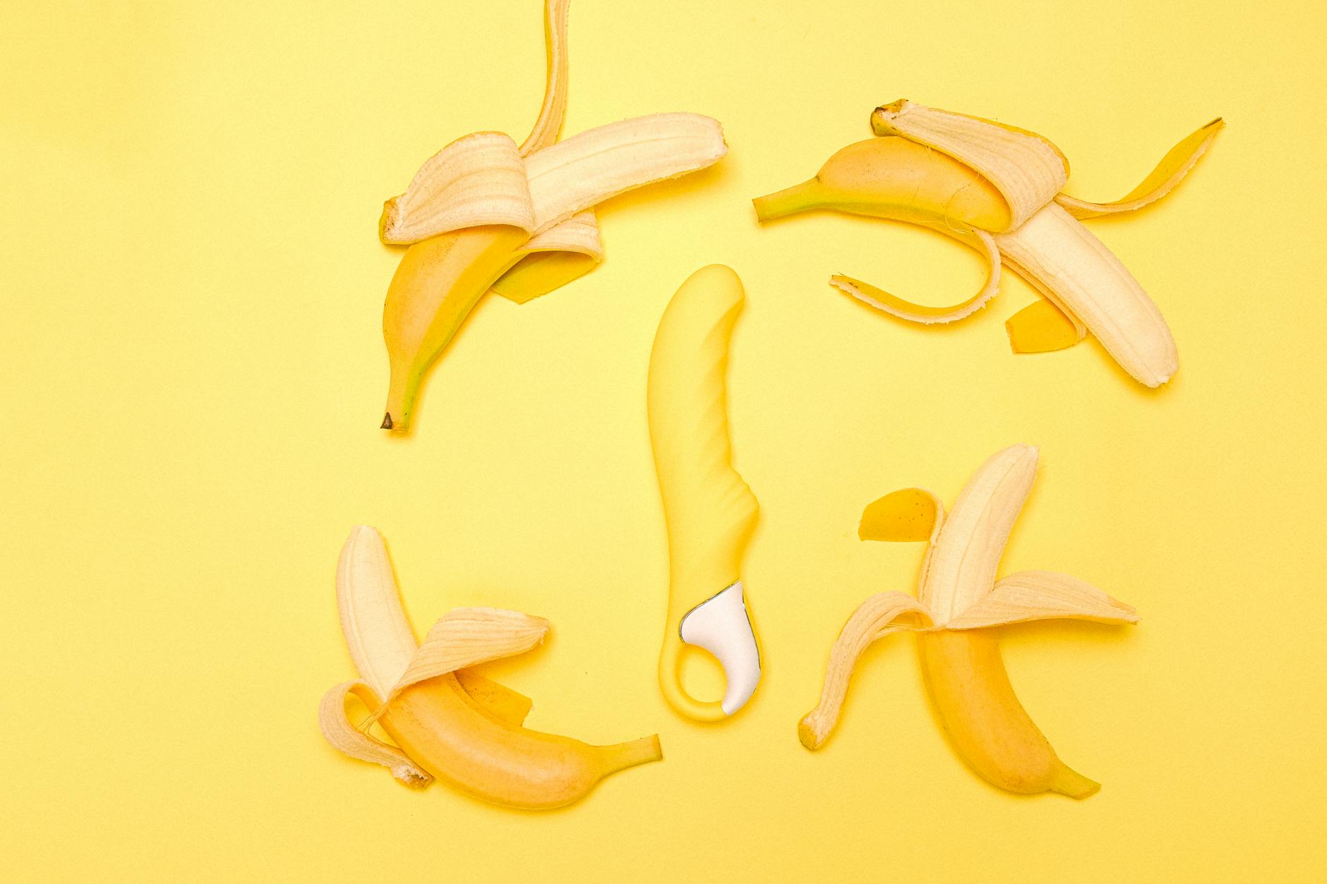 Bright yellow lemon vibrator on a yellow background with fresh lemons, symbolizing joy and simplicity in shared pleasure