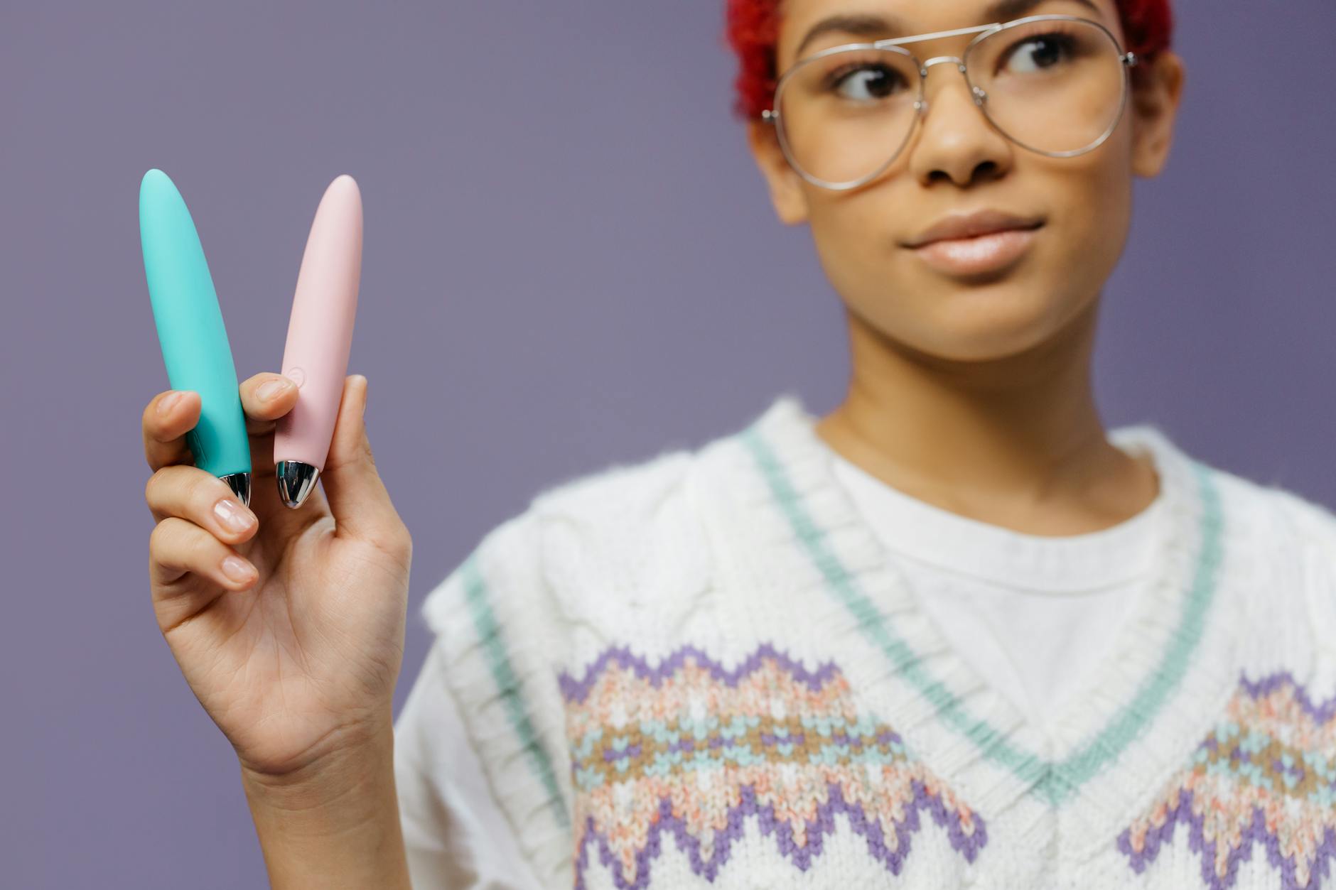 Woman holding vibrators and examining them with intention and focus