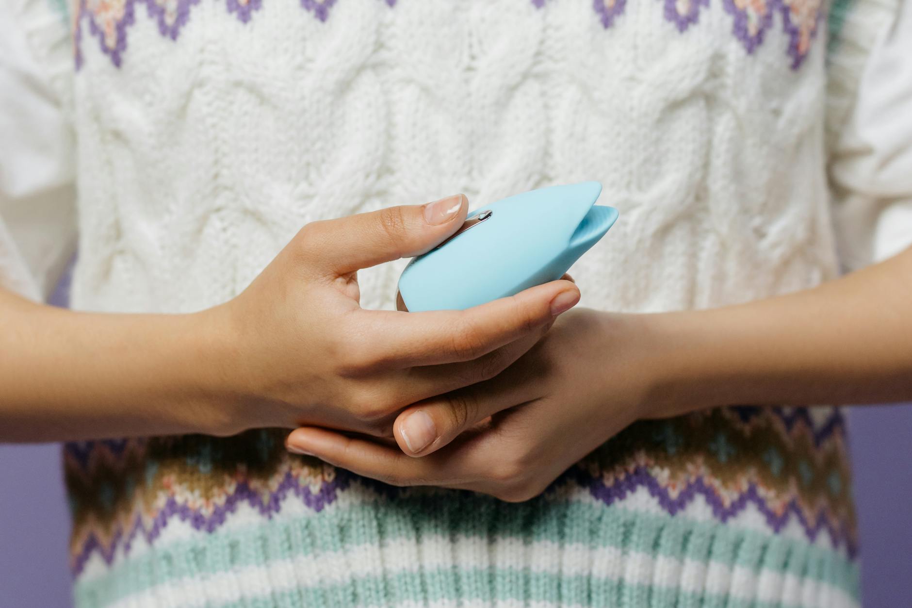 Hand reaching over a selection of colorful clitoral vibrators on a table