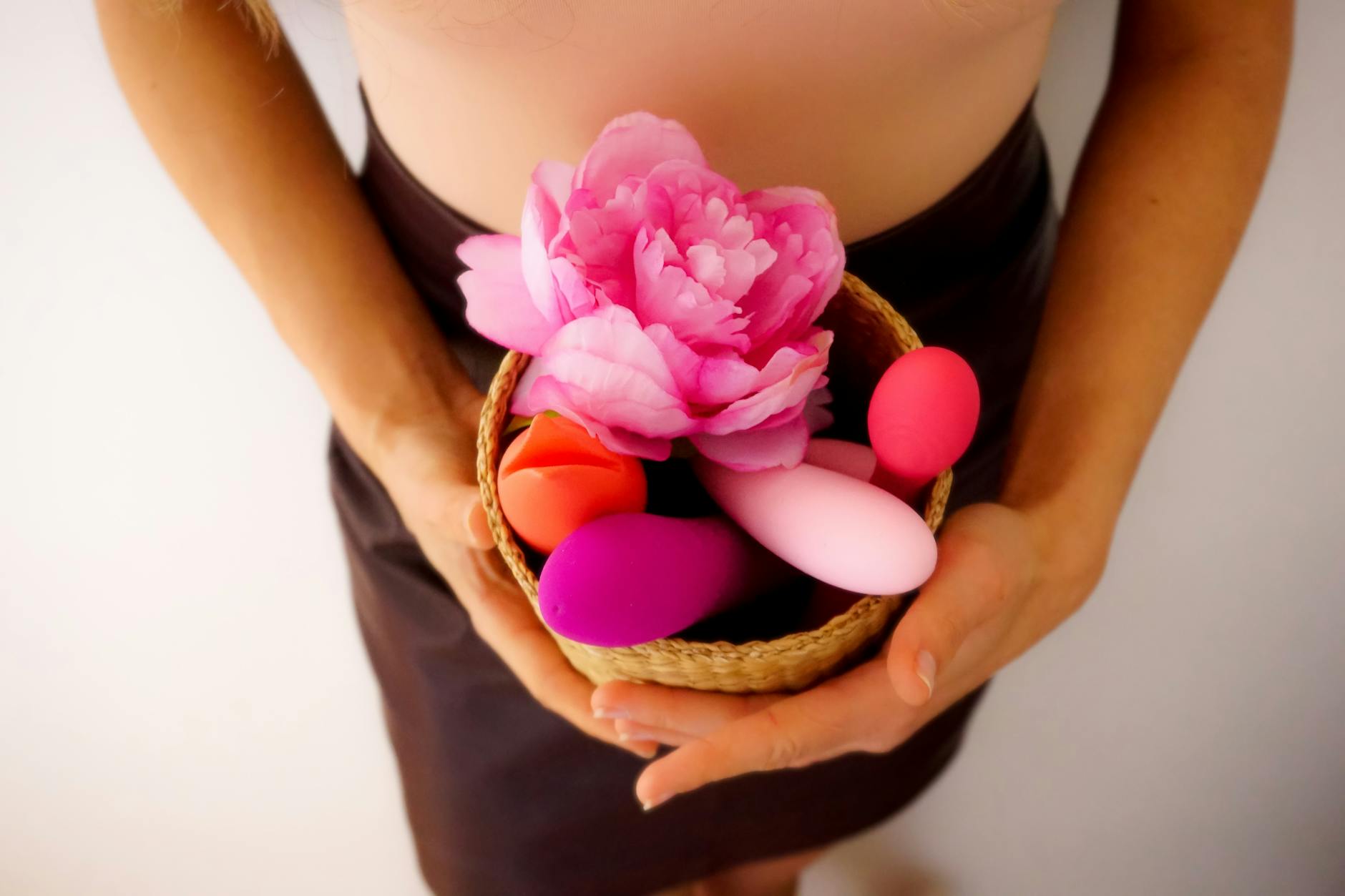Woman holding blue and pink silicone vibrators in a contemplative moment of self-care